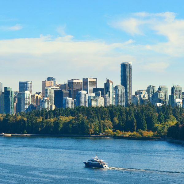 A boat floating on the ocean with the Vancouver skyline in the background under a clear sky.